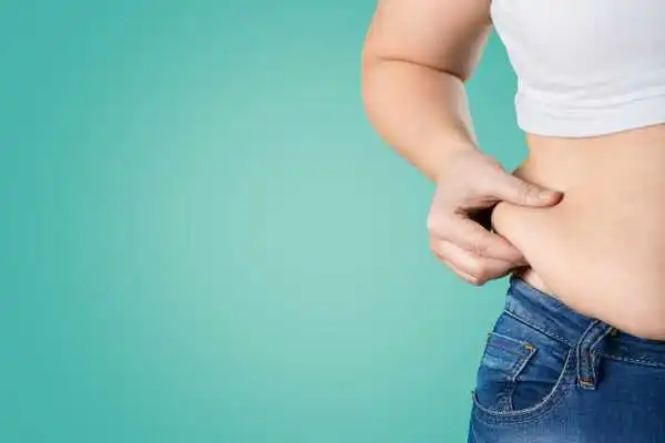 Image of woman pinching her love handles to show weight gain Swanage